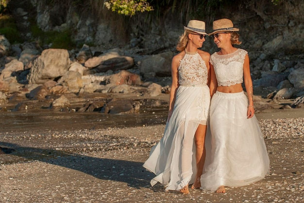 Two ladies wearing stylish hats and sunglasses at summer wedding