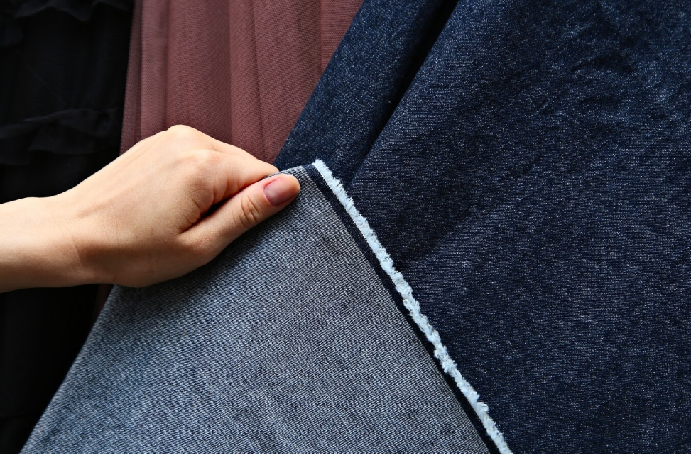 One hand is holding denim fabric.png
