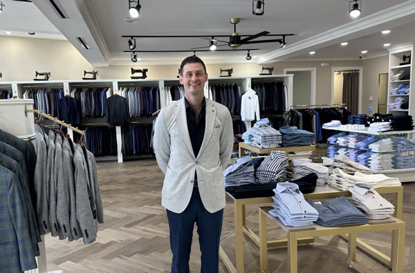 A man standing in a suit shop.png